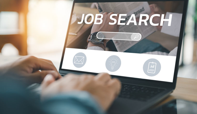 An image of a male typing on a laptop doing an online job search